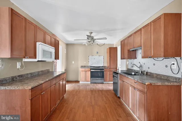 a kitchen with stainless steel appliances granite countertop wooden cabinets a stove top oven a sink and dishwasher
