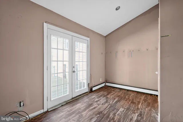 an empty room with wooden floor and windows