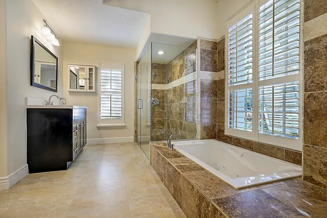 a bathroom with a granite countertop sink a toilet a mirror and shower
