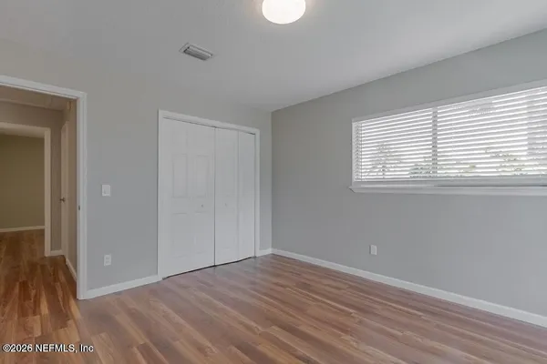 a view of an empty room with wooden floor and a window