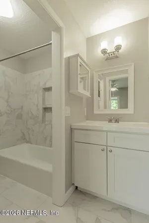 a bathroom with a bathtub sink vanity and mirror