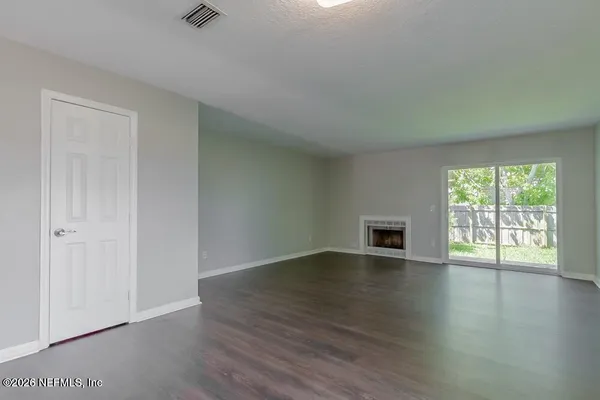 an empty room with wooden floor and windows