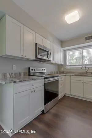 a kitchen with granite countertop white cabinets and white appliances