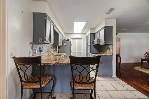 a kitchen with stainless steel appliances a dining table chairs and sink
