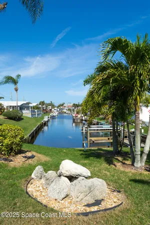 a backyard of a house with table and chairs potted plants and lake view