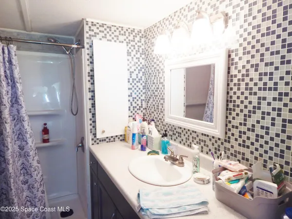 a bathroom with a sink vanity granite and a shower