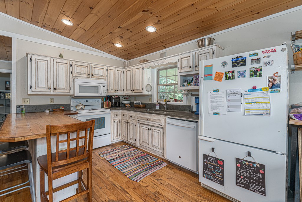 264 Tommy's Lane Murphy, NC 28906 - Photo 16 of 53 a kitchen with granite countertop a white refrigerator oven a sink dishwasher and white cabinets with wooden floor