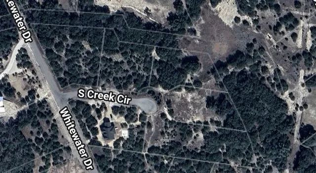 an aerial view of residential houses with outdoor space and trees