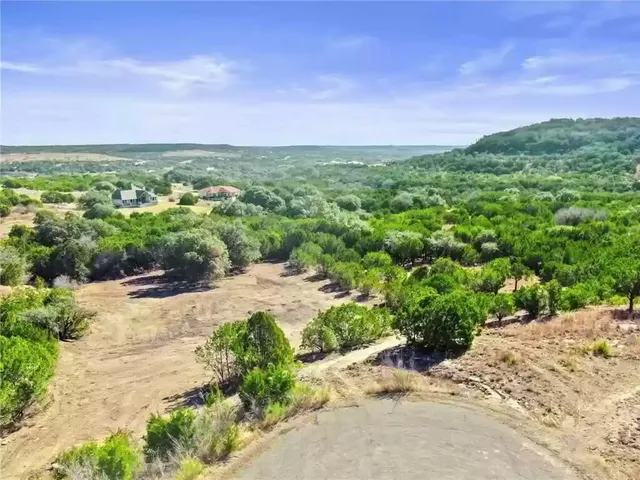 a view of dirt field with trees in the background