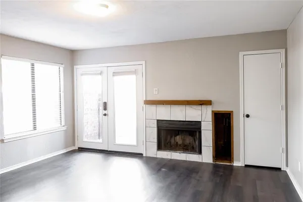an empty room with wooden floor fireplace and windows