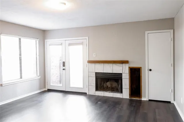 an empty room with wooden floor fireplace and windows