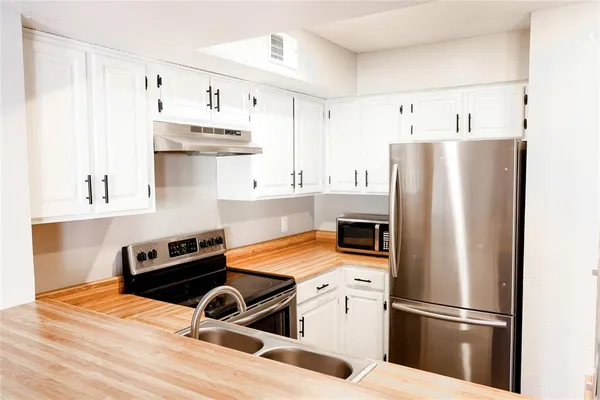 a kitchen with stainless steel appliances granite countertop a refrigerator a stove and a sink