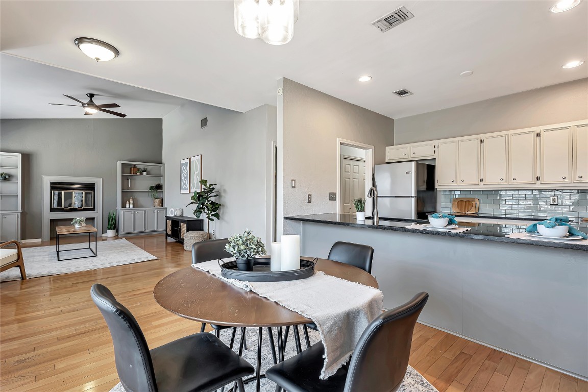 a kitchen with stainless steel appliances granite countertop a dining table chairs and refrigerator