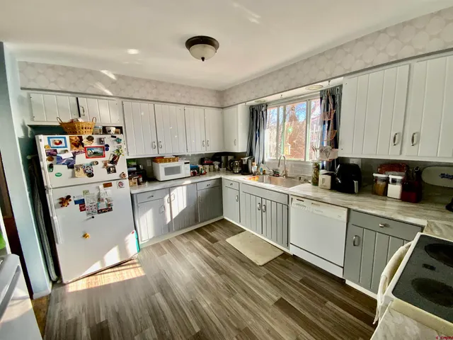 a kitchen with stainless steel appliances granite countertop a refrigerator sink and wooden cabinets