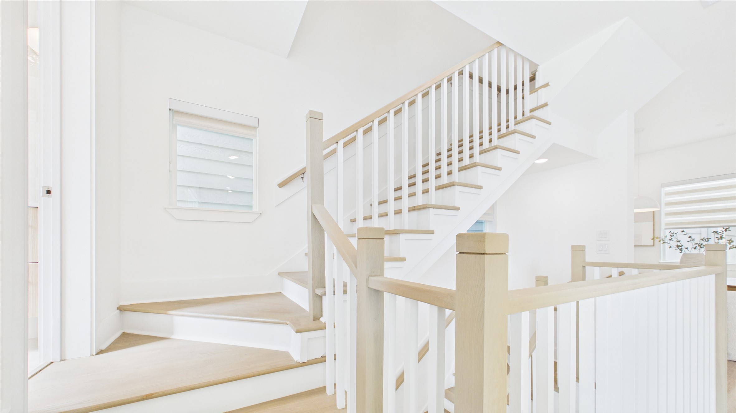 602 Skyland Terrace Way Houston, TX 77009 - Photo 14 of 40 This photo showcases a bright, modern staircase with light wood steps and white railings. The area is well-lit with natural light from a window, creating an airy and inviting atmosphere.