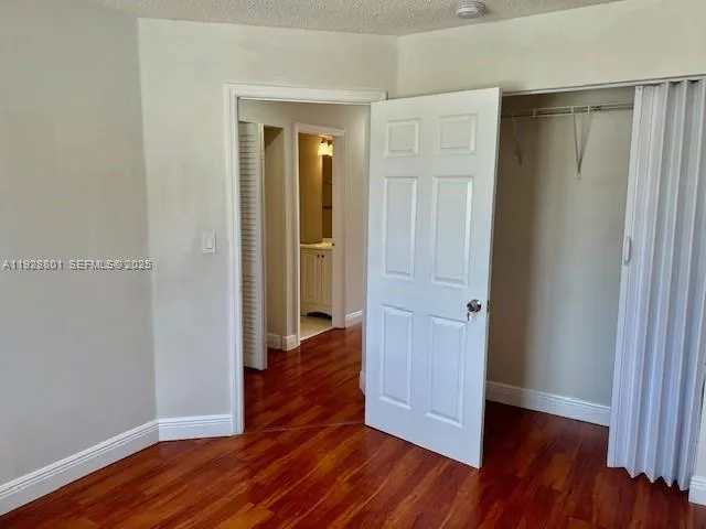 an empty room with wooden floor & closet area