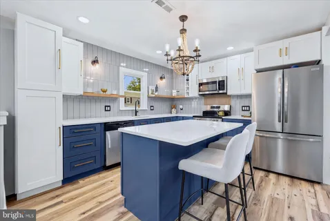 a large kitchen with cabinets a sink dishwasher a dining table and chairs with wooden floor