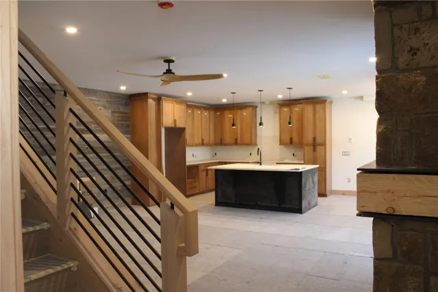 a large kitchen with a large counter top a sink stainless steel appliances and cabinets