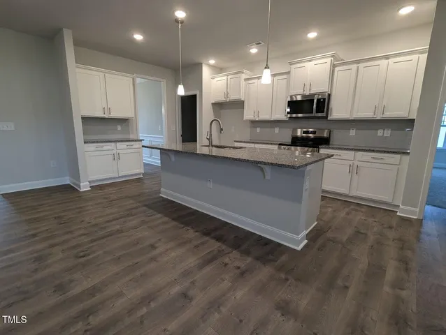 a view of kitchen with granite countertop stainless steel appliances refrigerator and cabinets