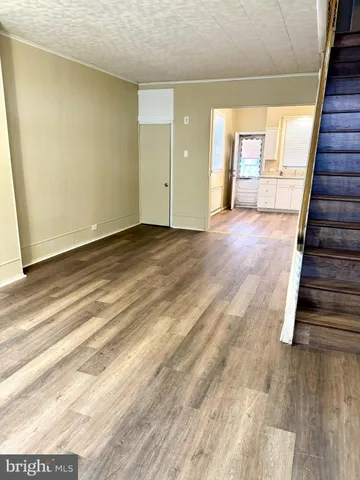 a view of an empty room with wooden floor and stairs