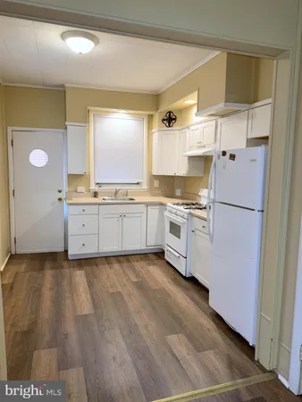 a kitchen with granite countertop a refrigerator a sink and white cabinets