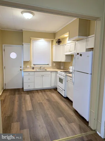 a kitchen with granite countertop a refrigerator a sink and white cabinets