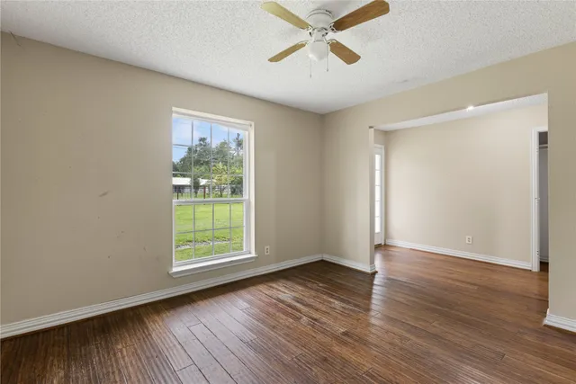 a view of an empty room with wooden floor and a window