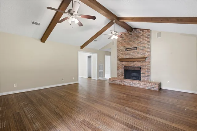 a view of empty room with wooden floor and fireplace