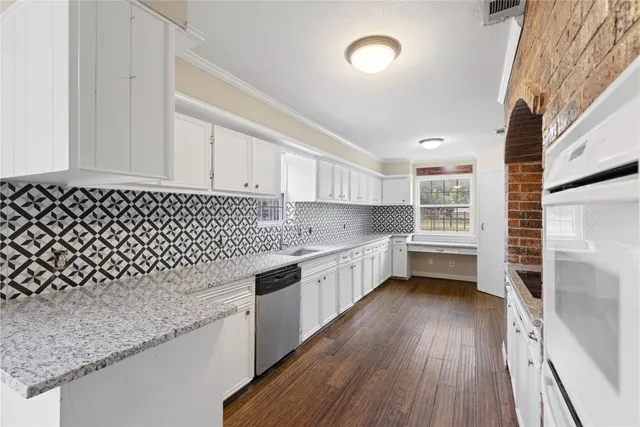 a kitchen with granite countertop a sink a stove and wooden floor