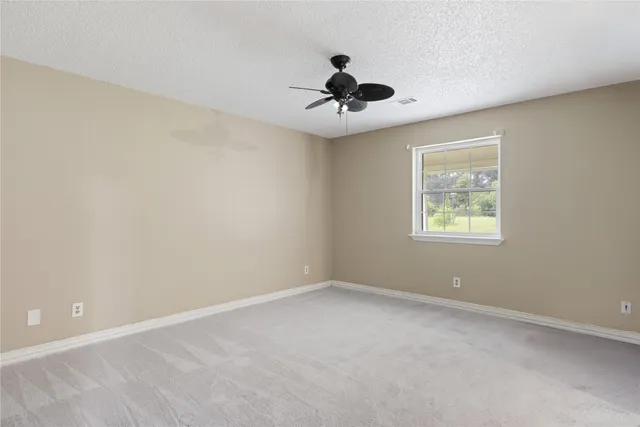 an empty room with a window and a fan