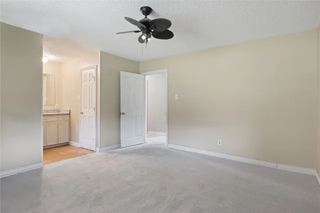 a view of an empty room and chandelier fan