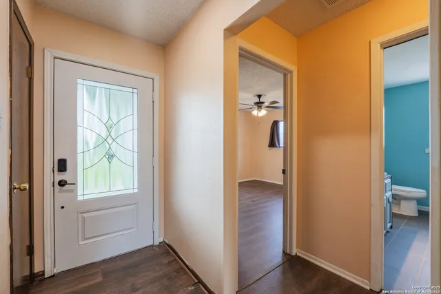 a view of an empty room with wooden floor and a ceiling fan