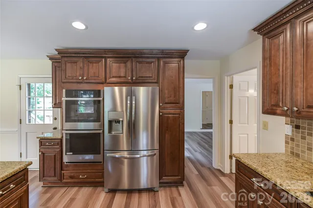 a kitchen with stainless steel appliances granite countertop a refrigerator and a stove top oven