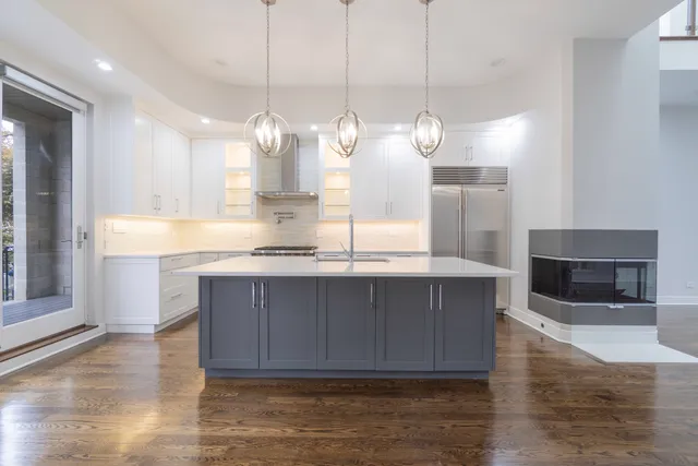 a kitchen with kitchen island granite countertop wooden cabinets and a fireplace