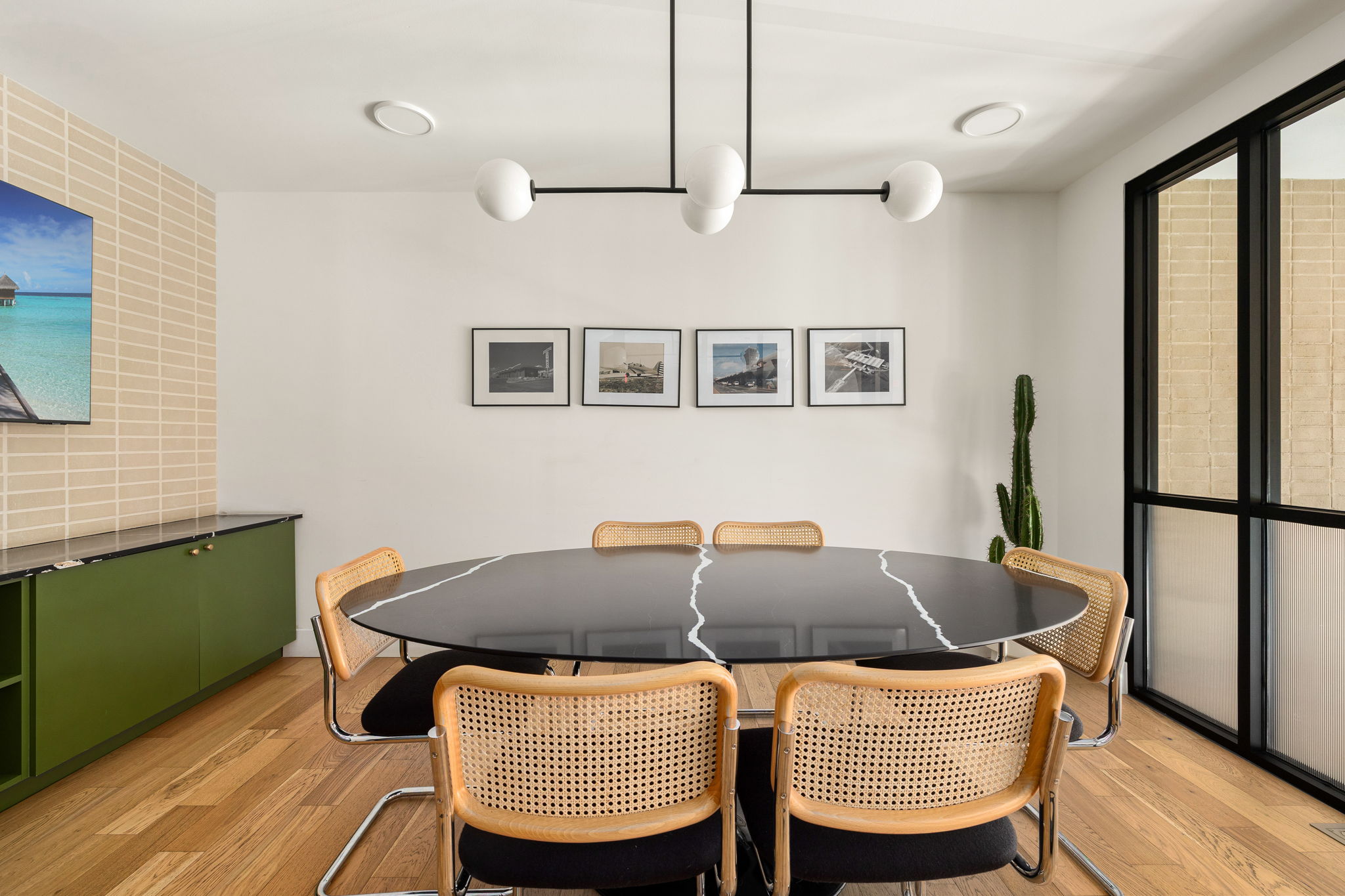 1701 Simond Avenue, Unit 612 Austin, TX 78723 - Photo 34 of 40 Hardwood flooring complements a contemporary chandelier, a built-in green credenza with a black countertop, and a black-framed window