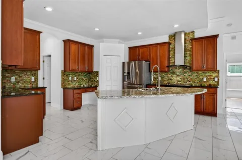 a kitchen with stainless steel appliances kitchen island granite countertop a refrigerator and a sink