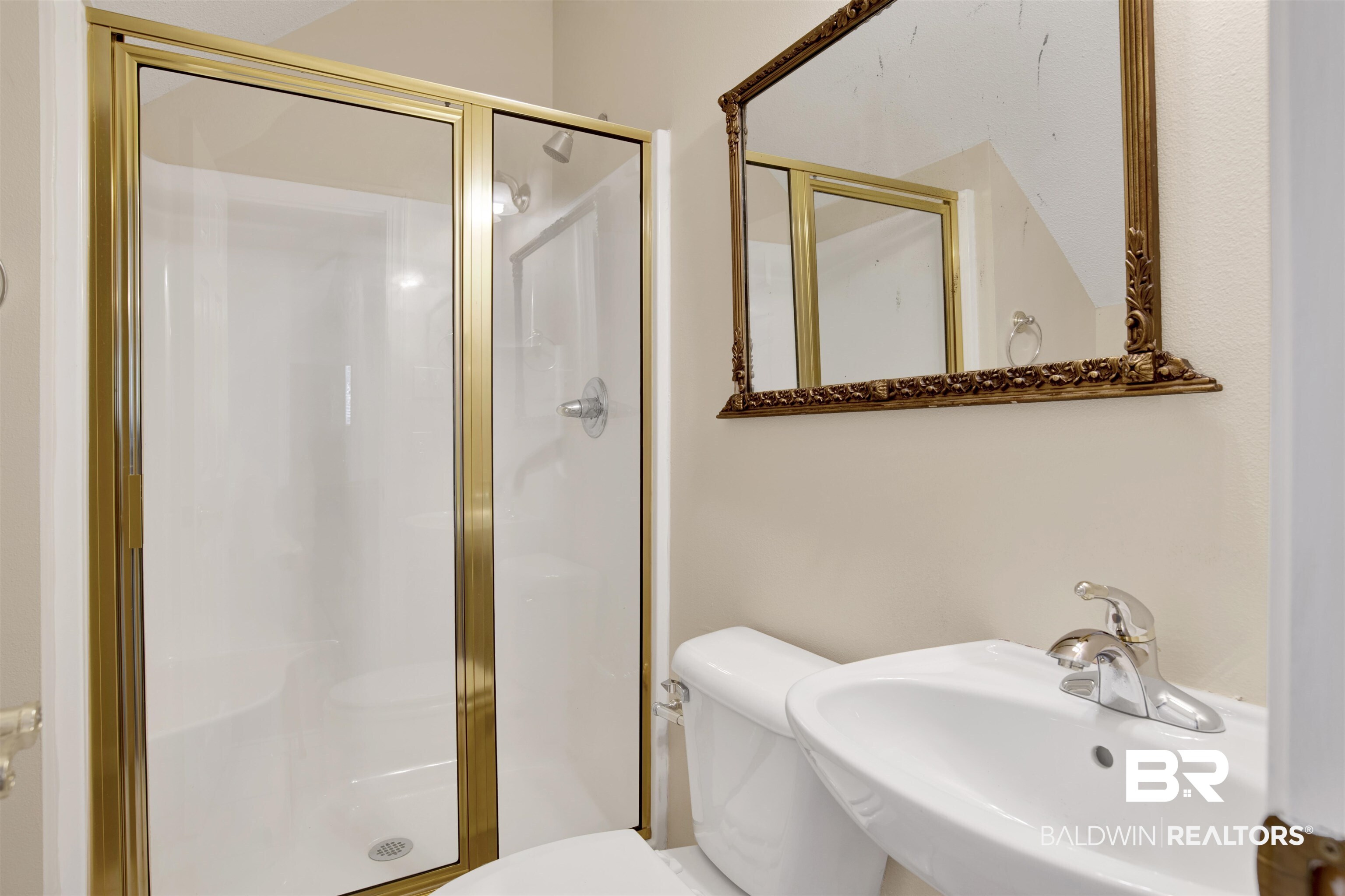 8847 Dawes Lake Road South Mobile, AL 36619 - Photo 32 of 47 Shower stall with polished brass frame, single-handle chrome faucet, white pedestal sink, and decorative wall mirror