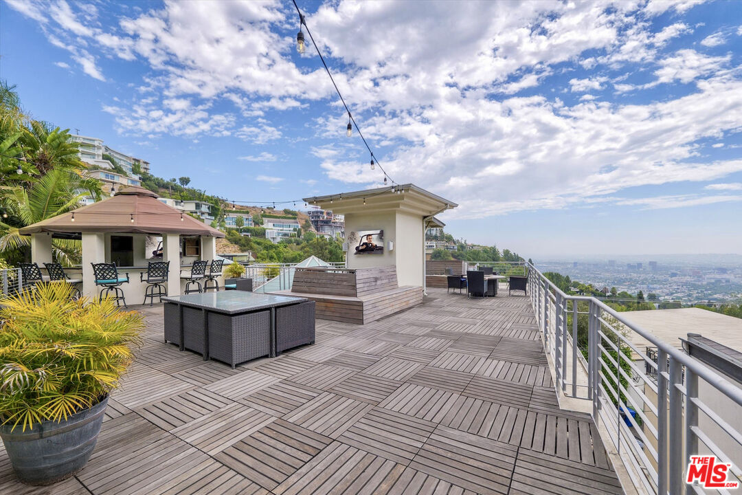 a view of a patio with couches table and chairs under an umbrella with wooden floor