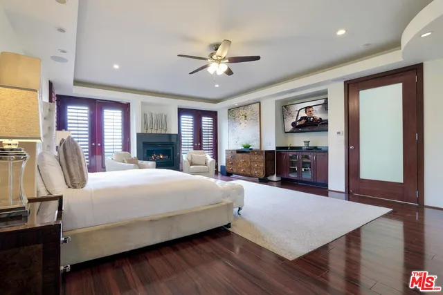 a bedroom with a large bed a flat tv screen and dresser