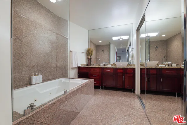 a bathroom with a bathtub a double vanity sink and mirror