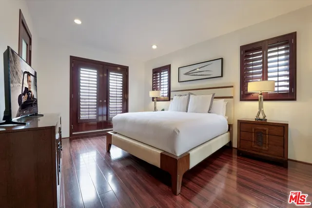 a bedroom with a bed and a flat tv screen on dresser