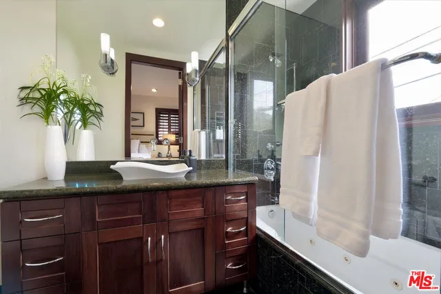 a bathroom with a granite countertop sink a mirror and a shower