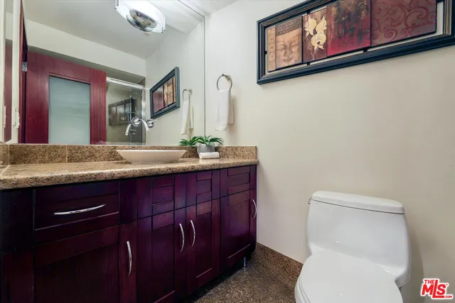 a bathroom with a granite countertop toilet sink and mirror