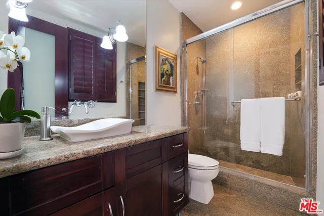 a bathroom with a granite countertop sink toilet a large mirror a shower and a bathtub