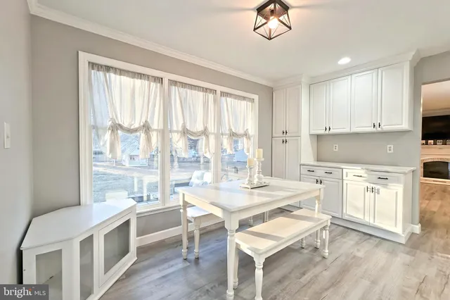 a kitchen with a stove a sink a refrigerator and white cabinets with wooden floor