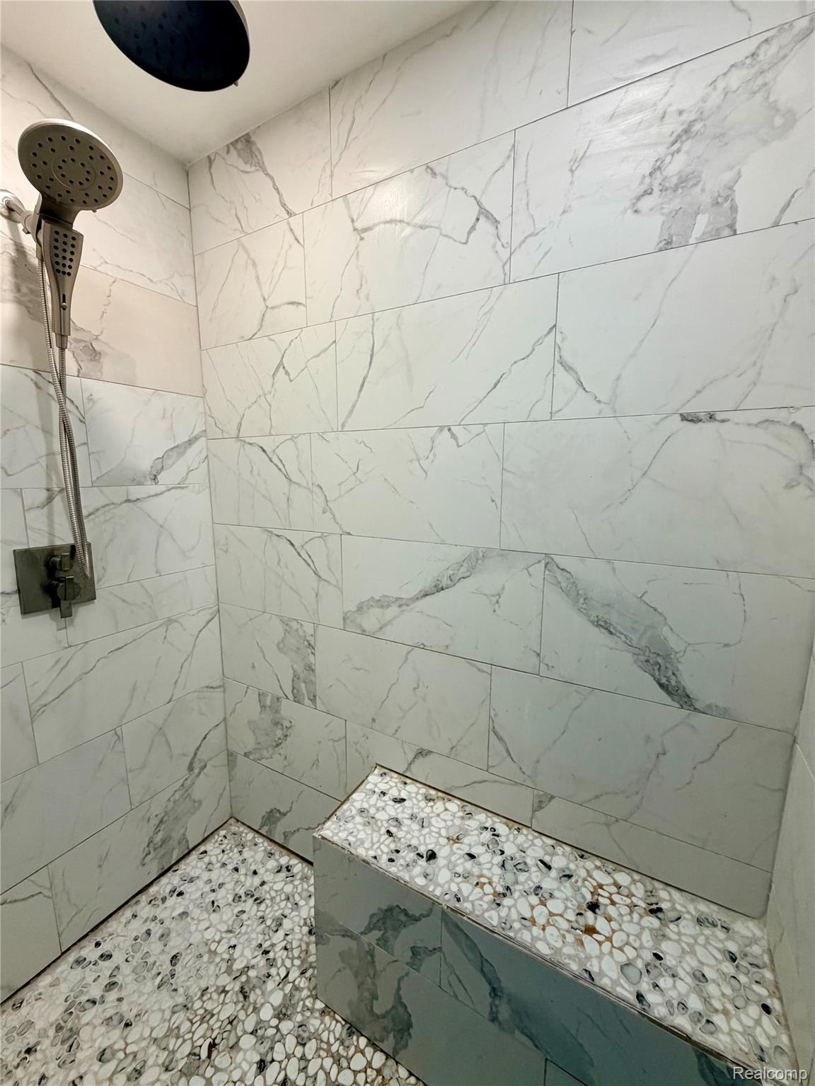 3840 East Dunbar Road Monroe, MI 48161 - Photo 26 of 38 Shower with white marble-look subway tile walls, a built-in bench with pebble-style top, and pebble-style flooring