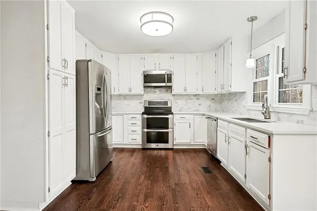 a kitchen with stainless steel appliances granite countertop a stove and white cabinets