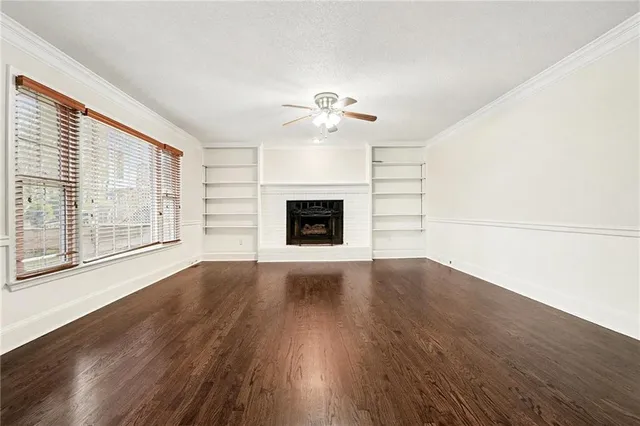 a view of an empty room with wooden floor fireplace and a window