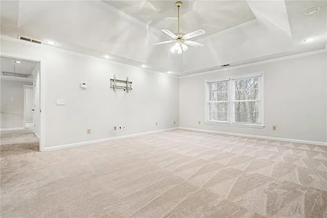 an empty room with chandelier fan and windows