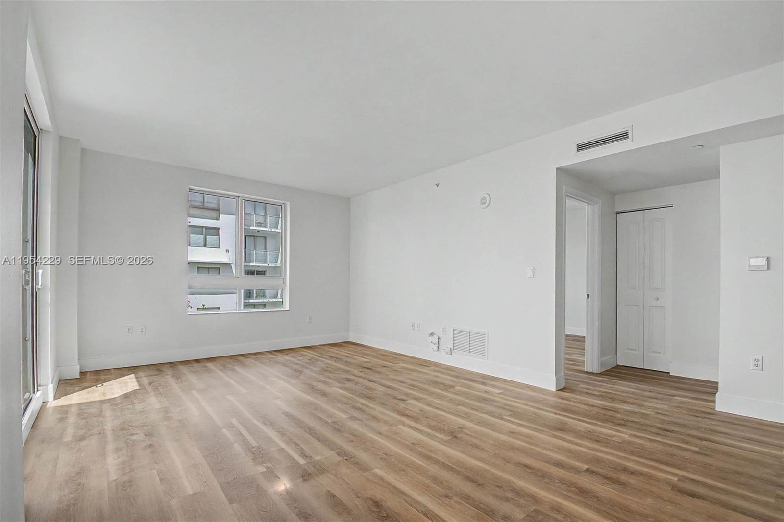 7355 Southwest 89th Street, Unit 502N Miami, FL 33156 - Photo 2 of 15 a view of an empty room with wooden floor and a window
